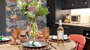 A dining table set with plates, glasses, a bottle of wine, and a vase of flowers.