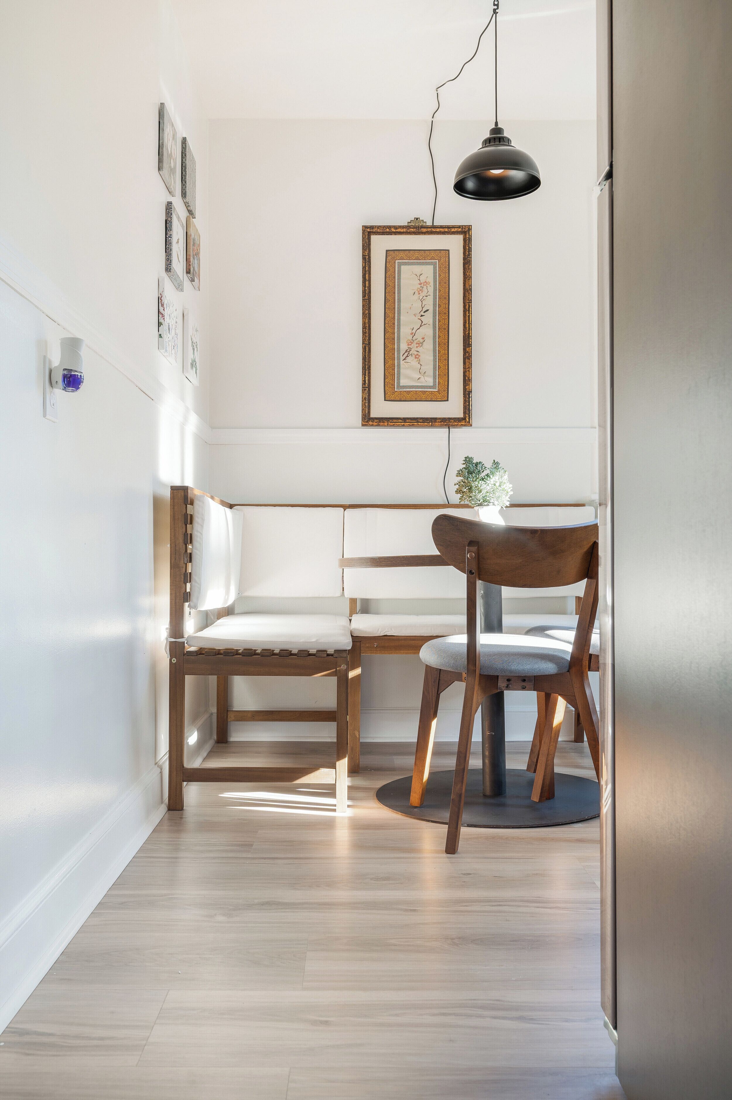 Une cuisine moderne avec des meubles en bois, un coin repas comprenant un banc et des chaises, et un luminaire suspendu.