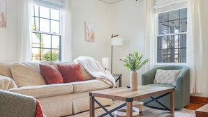 A living room with a sofa, a green armchair, a wooden coffee table, and a floor lamp. - Sage & Stone cottage-2BR near Downtown Lynchburg & LU (Lynchburg)