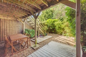 A wooden pergola with a table and chairs underneath, surrounded by a garden with various plants and a wooden deck. - 2 Bed in Shoreham-by-Sea (oc-b29920) (Shoreham-by-Sea)