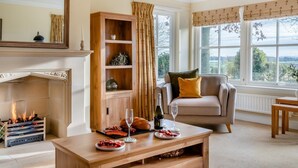 Un salon chaleureux avec une cheminée, un meuble en bois, un canapé et une table à manger où sont disposés de la nourriture et des boissons.