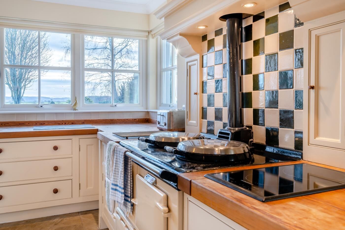 A kitchen with a stove, oven, and a window with a view of trees.
