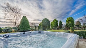 Un bain à remous entouré d’un jardin aménagé, agrémenté de différents arbres et arbustes.
