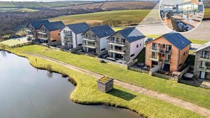 Een rij moderne huizen met uitzicht op een meer en glooiende heuvels op de achtergrond.