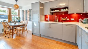 Eine moderne Küche mit grauen Schränken, einem Holztisch und einer roten Akzentwand.