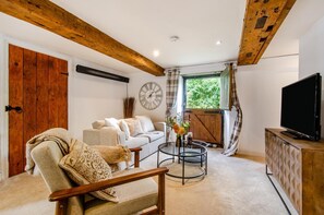 A living room with a sofa, armchair, coffee table, TV, and a window with curtains. - 1 Bed in Sedgeberrow (oc-w30007) (Sedgeberrow)