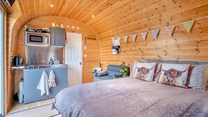 A cozy cabin interior with a bed, a kitchenette, and a seating area. - 1 Bed in Cross (oc-s29656) (Cross)