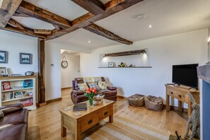 A living room with a leather sofa, wooden coffee table, and a TV on a wooden stand.