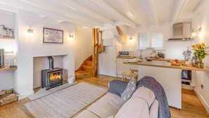 A cozy living room with a fireplace, a sofa, and a kitchen area with a wooden island. - 1 Bed in Whitby (oc-e29968) (Egton Bridge)