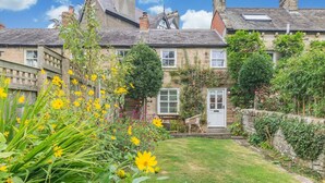 A traditional stone house with a well-maintained garden, a wooden fence, and a clear view of the surrounding area. - 1 Bed in Whitby (oc-e29968) (Egton Bridge)