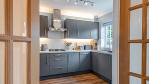 Una cocina moderna con gabinetes grises, una campana extractora de acero inoxidable y un ventanal que proporciona luz natural.