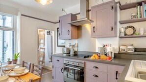 Una cocina moderna con una isla central, horno empotrado y un comedor con mesa y sillas de madera.