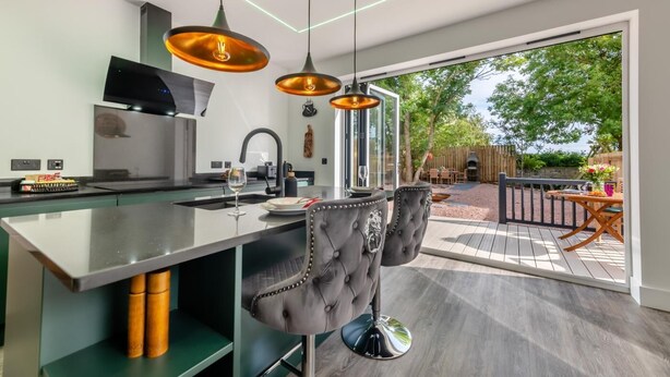 A modern kitchen with a large island, bar stools, and pendant lighting. - 4 Bed in Berwick-upon-Tweed (oc-h29940) (Cheswick Buildings)
