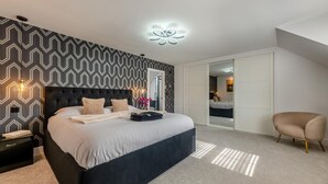 A modern bedroom with a large bed, a nightstand, a chair, and a walk-in closet. - 4 Bed in Berwick-upon-Tweed (oc-h29940) (Cheswick Buildings)