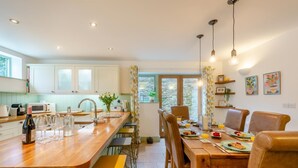 Uma cozinha moderna com ilha de madeira, armários brancos e área de jantar com mesa e cadeiras de madeira.