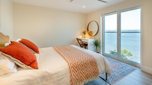 A bedroom with a bed, a desk, a chair, a large window with a view of the water, and a ceiling light. - 2 Bed in Tayport (oc-w30005) (Dundee)