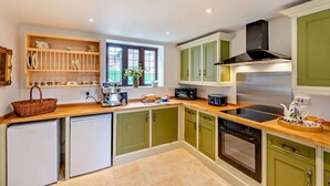 Una cocina moderna con armarios verdes, horno empotrado, microondas y cafetera.