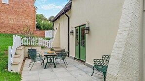 Un patio con una mesa y sillas, una puerta verde y una valla de piquetes blancos.