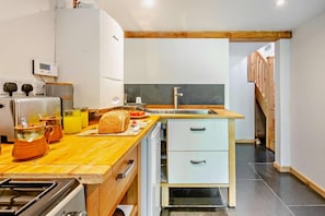 A modern kitchen with a wooden countertop, stainless steel appliances, and a built-in dishwasher. - 1 Bed in Brithdir (oc-w30045) (Brithdir and Llanfachreth)
