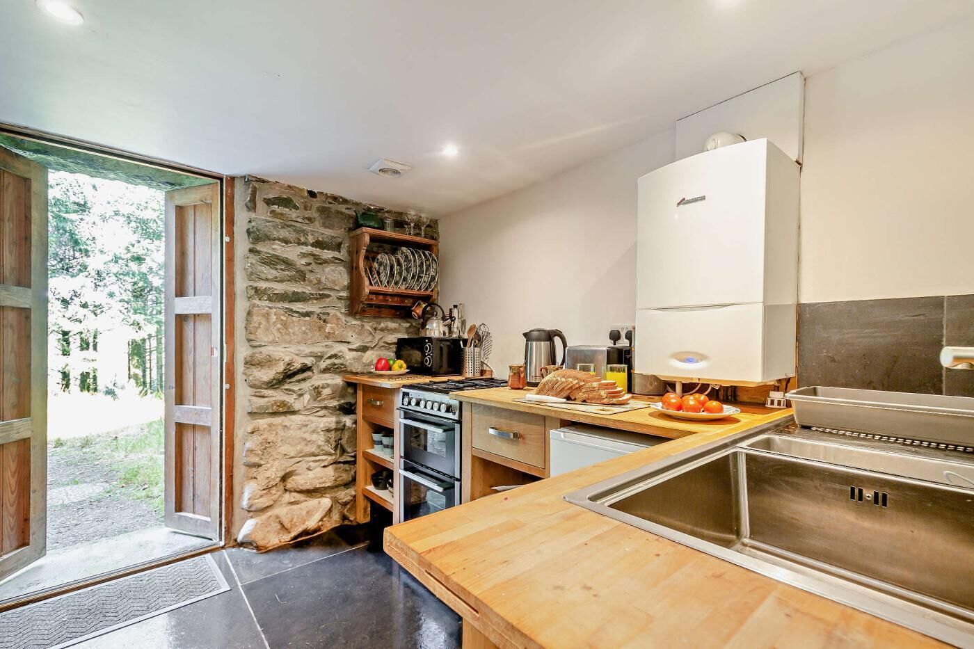 A modern kitchen with a stone wall, wooden cabinets, and a built-in oven.