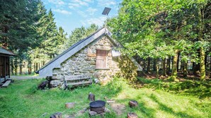 A stone cabin with a sloped roof, a wooden door, and a small porch.