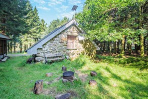 A stone cabin with a sloped roof, a wooden door, and a small porch.