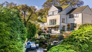 Ein modernes, zweistöckiges Haus mit großem Garten, Sitzgelegenheiten im Freien und einem Whirlpool.