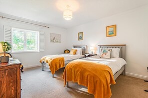 Een slaapkamer met twee bedden, een bureau en een raam.