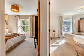 A hotel room with a large bed, a desk, a chair, a television, and a view of the outdoors. - 3 Bed in Cromer (oc-r30071) (Cromer)