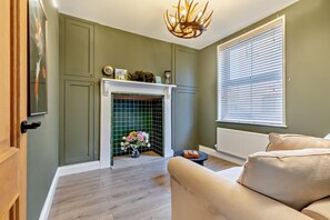 A room with a fireplace, a sofa, and a window with blinds. - 3 Bed in Cromer (oc-r30071) (Cromer)