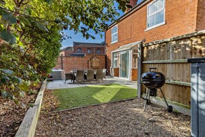 A backyard with a barbecue grill, outdoor seating, and a grassy lawn. - 3 Bed in Cromer (oc-r30071) (Cromer)