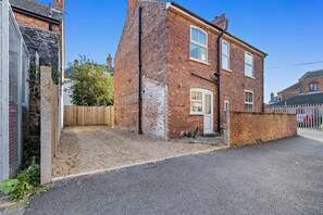A two-story brick house with a front door, a small porch, and a fenced backyard. - 3 Bed in Cromer (oc-r30071) (Cromer)
