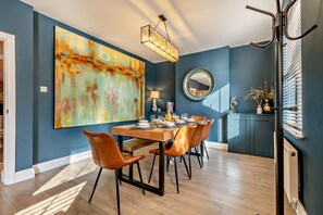 A dining area with a large abstract painting, a round mirror, and a modern chandelier. - 3 Bed in Cromer (oc-r30071) (Cromer)
