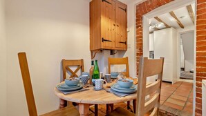 A dining area with a wooden table, chairs, and a brick wall. - 2 Bed in Lavenham (oc-s30055) (Lavenham)