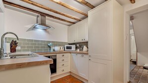 A kitchen with white cabinets, a built-in dishwasher, a microwave, and a sink with a modern faucet. - 2 Bed in Lavenham (oc-s30055) (Lavenham)