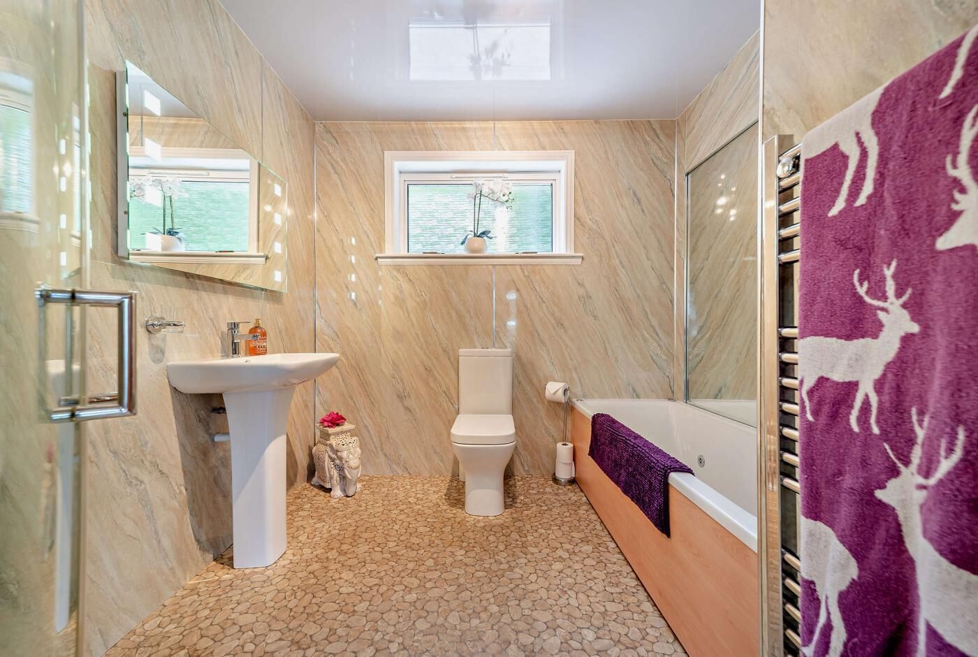 Ein Badezimmer mit Marmorboden, Waschbecken, Toilette, Badewanne und einem Fenster mit Blick.