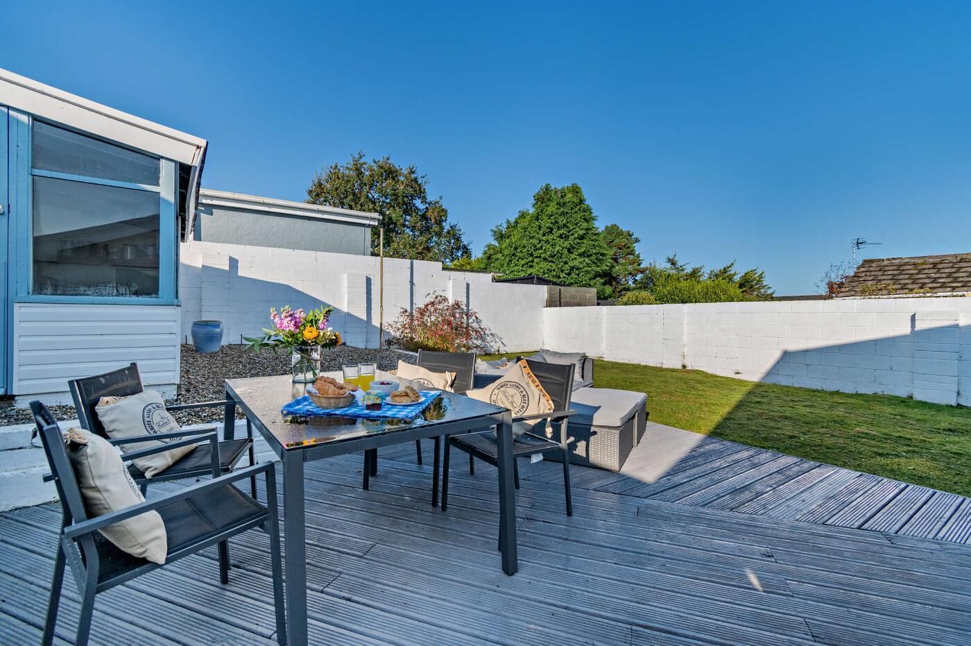 An outdoor patio with a table, chairs, and a small garden area.