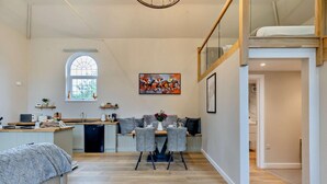 Une cuisine moderne avec un coin repas, une grande fenêtre et une chambre à coucher située en mezzanine.