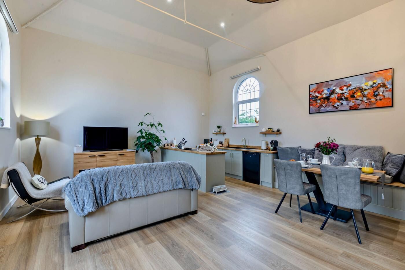 A modern living room with a sofa, TV, and a dining area with chairs and a table.