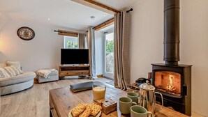 A cozy living room with a fireplace, a television, and a dining area with waffles and mugs. - 3 Bed in Hartington (oc-h30059) (Hartington Nether Quarter)