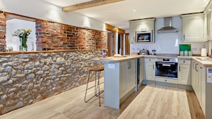 A modern kitchen with stone walls, wooden beams, and light-colored cabinets. - 3 Bed in Hartington (oc-h30059) (Hartington Nether Quarter)