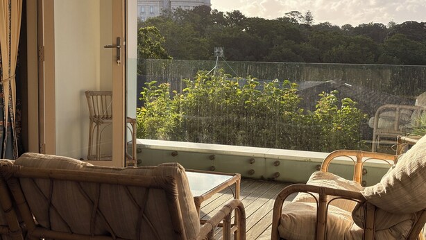 Varanda com mobiliário de vime e vista para a cidade.