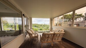 Varanda com mobiliário de vime e vista para a cidade.