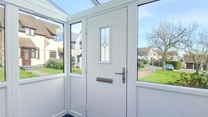 A conservatory with a white door and glass panels, offering views of a residential street. - 2 Bed in Padstow (oc-t30052) (Padstow)