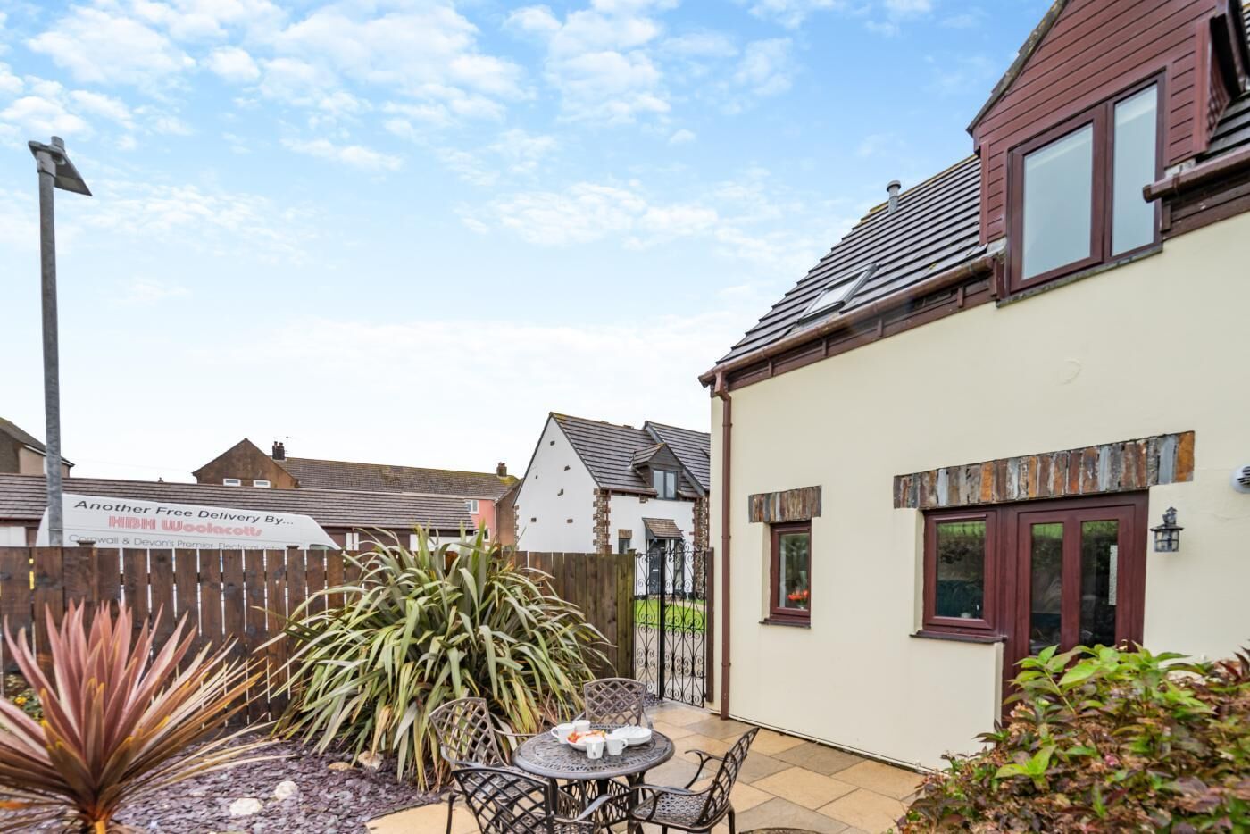 A residential property with a patio area, a table with chairs, and a wooden fence.