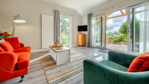 Ein modernes Wohnzimmer mit großem Fenster, einem Flachbildfernseher und einer Holzschrankwand.