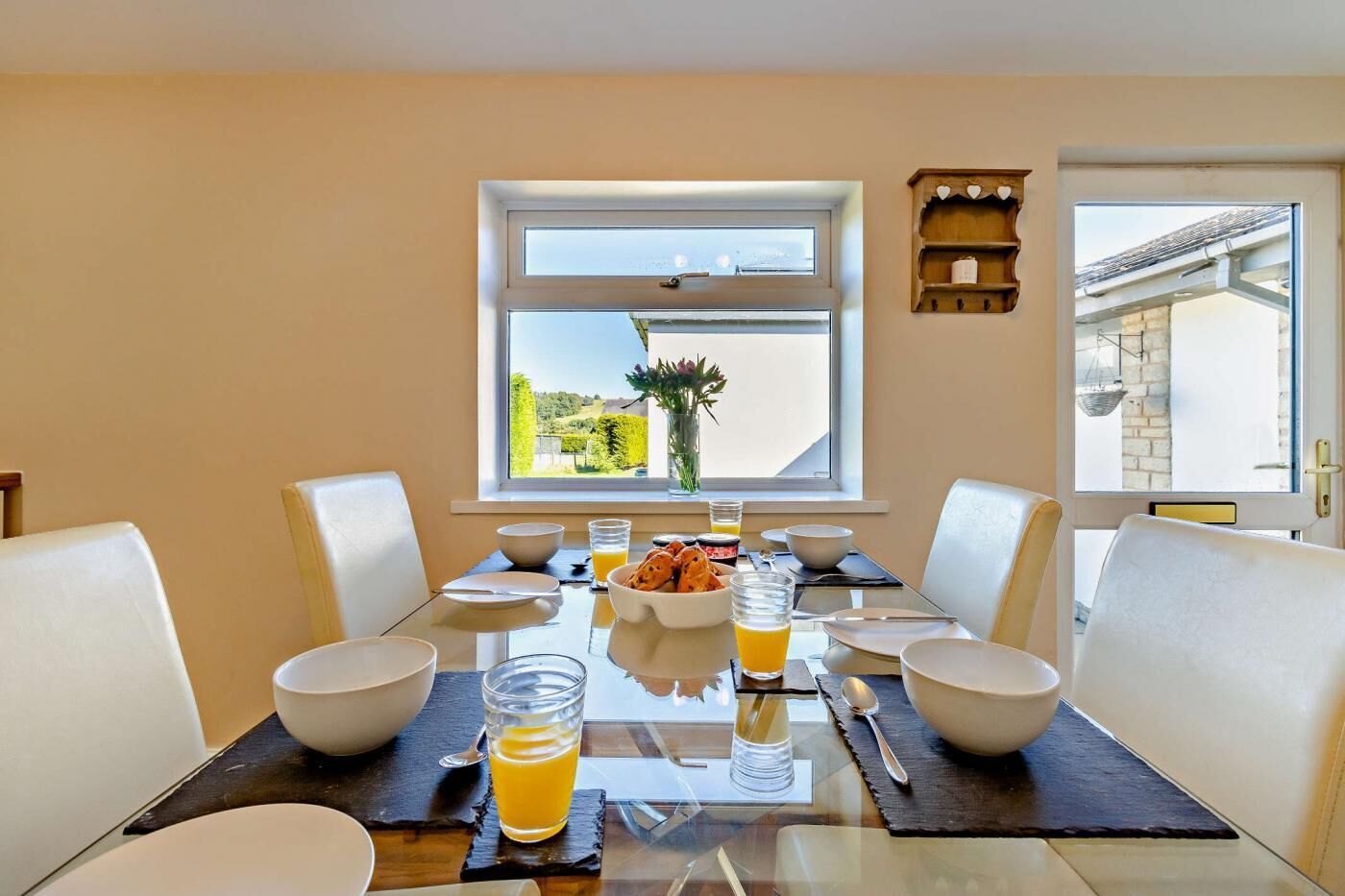 A dining table set for four with bowls, glasses, and a vase of flowers.