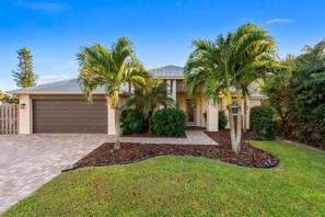 A residential house with a garage, palm trees, and a well-maintained lawn. - 120 S 5th Street (Cocoa Beach)
