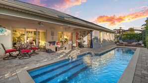 Ein Swimmingpool mit Terrassenbereich, Gartenmöbeln und einem Haus mit überdachter Veranda.