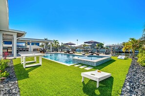 Uma área de piscina com grama sintética, espreguiçadeiras e mesa de bilhar.